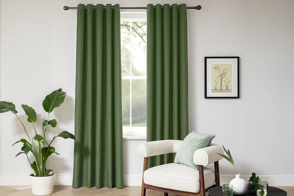 An Argos Home plain blackout green eyelet curtain on a window near a frame hanging on the wall.