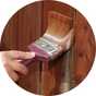 A person painting a fence with Johnstone's - Shed & Fence Paint - Red Cedar - 9L.
