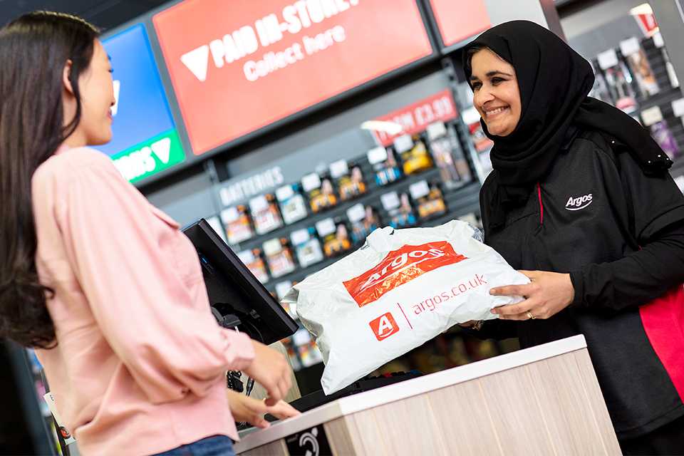 A woman returning an Argos order to a woman at an Argos counter.