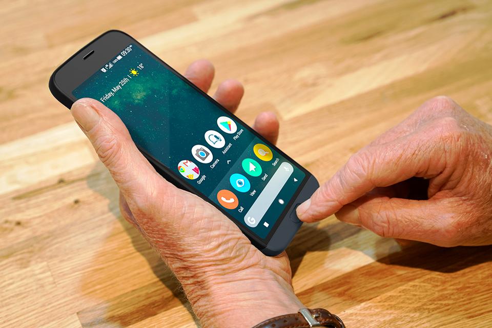 The image shows two hands holding a Doro 8050 phone on a wooden table. One finger is poised to press a button.