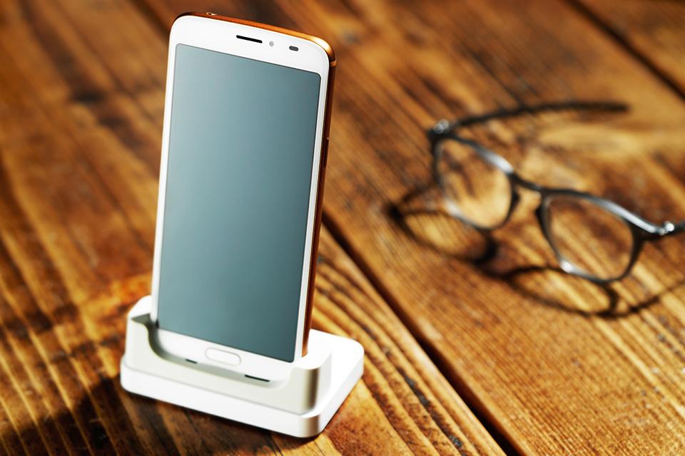 The Doro 8080 is placed on a wooden table, next to a pair of glasses.