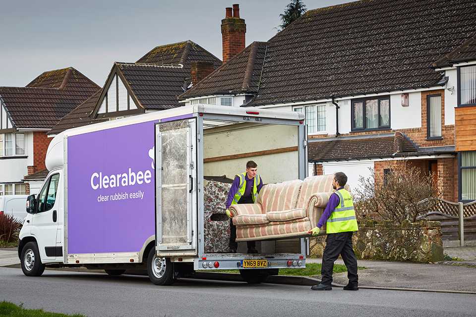 Clearbee staff loading an old sofa into a truck.