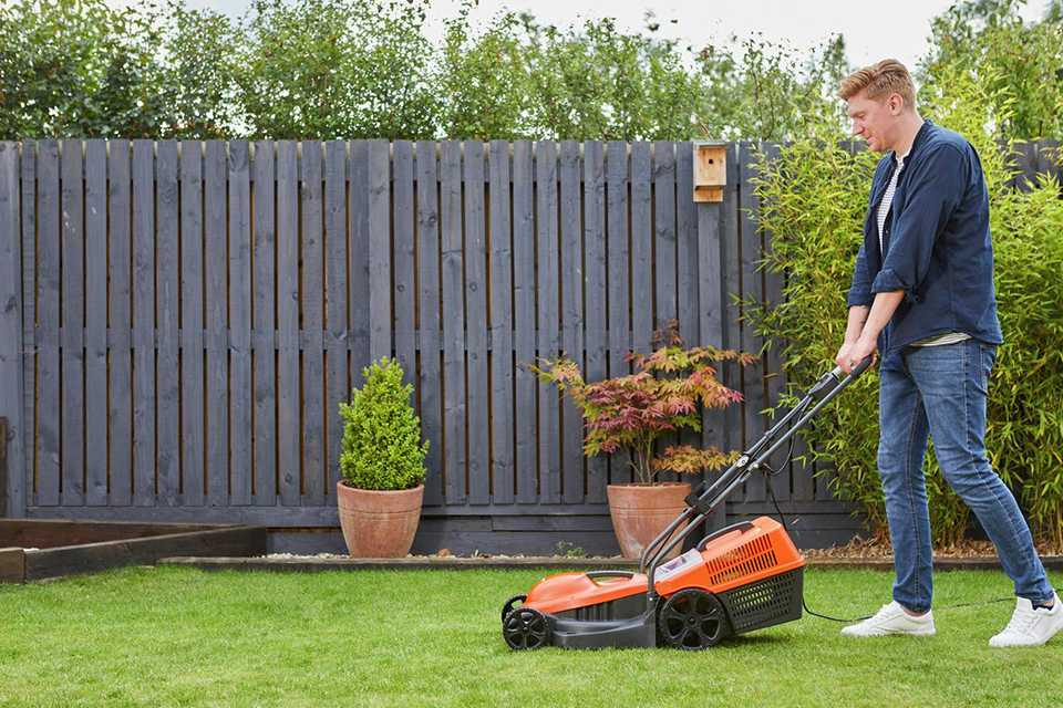 A man using Flymo SimpliMow 32cm corded rotary lawnmower.