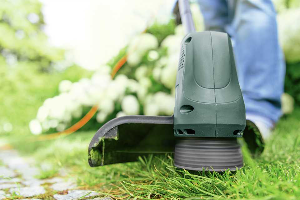 A person using 280W Bosch 23cm corded grass trimmer.