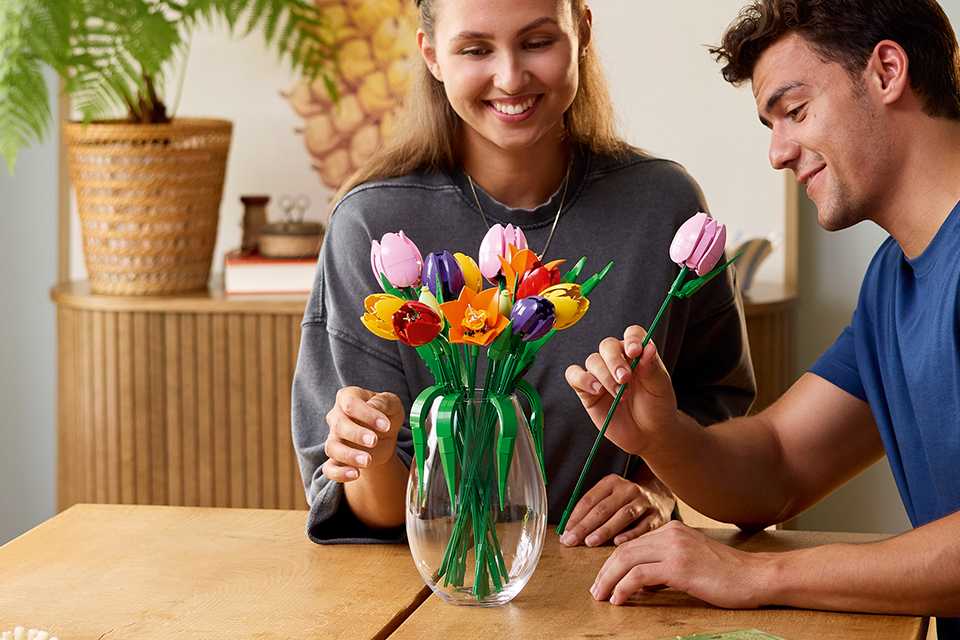 Man and woman arranging LEGO flowers in a vase.