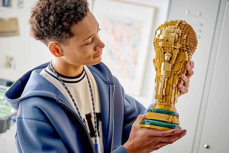A boy holding up and admiring the LEGO World Cup Trophy set.