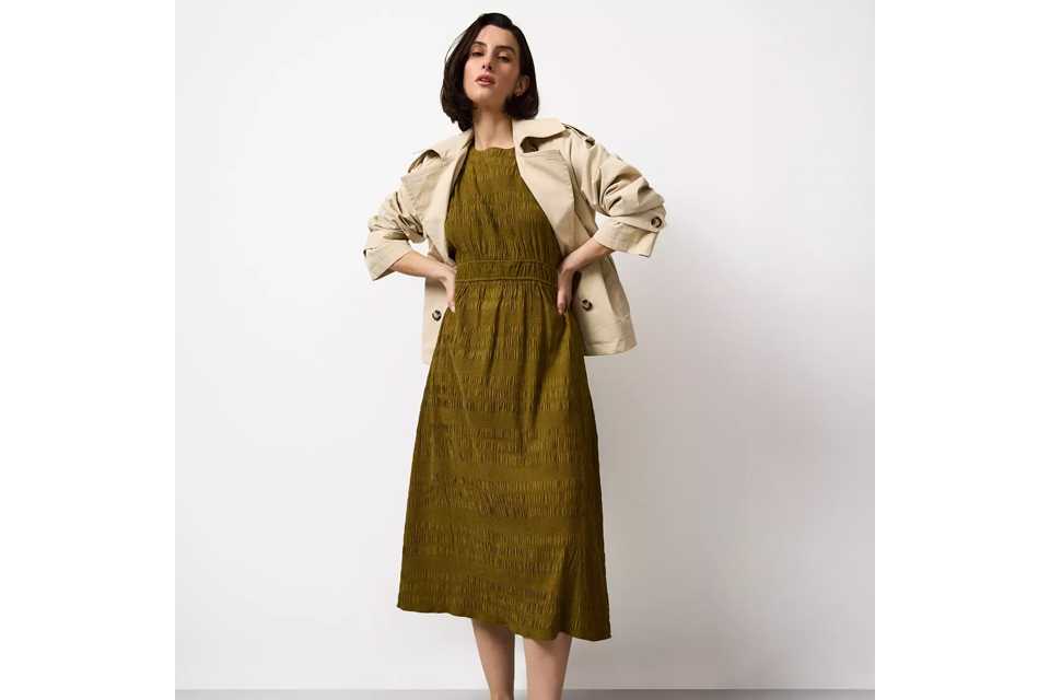 Light blue striped midi dress with short puff sleeves, V‑neckline and button‑front detail, styled with black ballet flats on a white background.