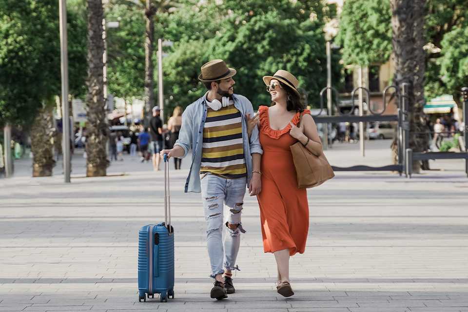 A happy couple on vacation walking with a suitcase.