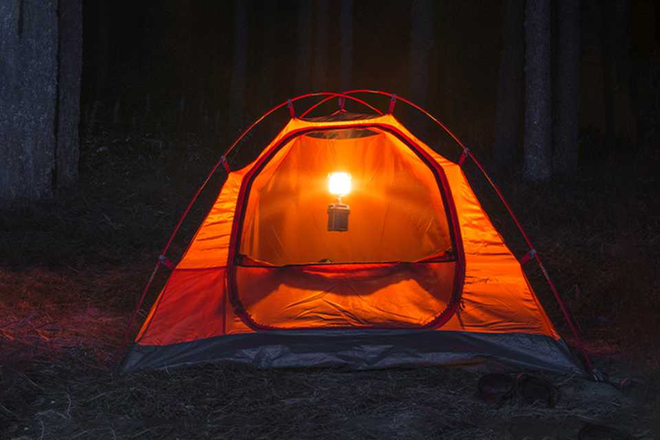 A lantern hanging in a tent at night.