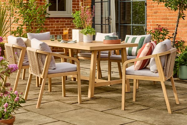 A Habitat Hania 6 seater wooden patio set in natural finish placed outdoors.