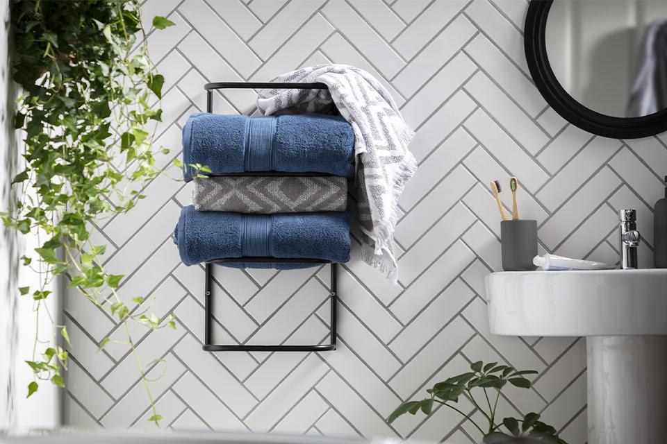 A black towel rack containing a stack of different towels.