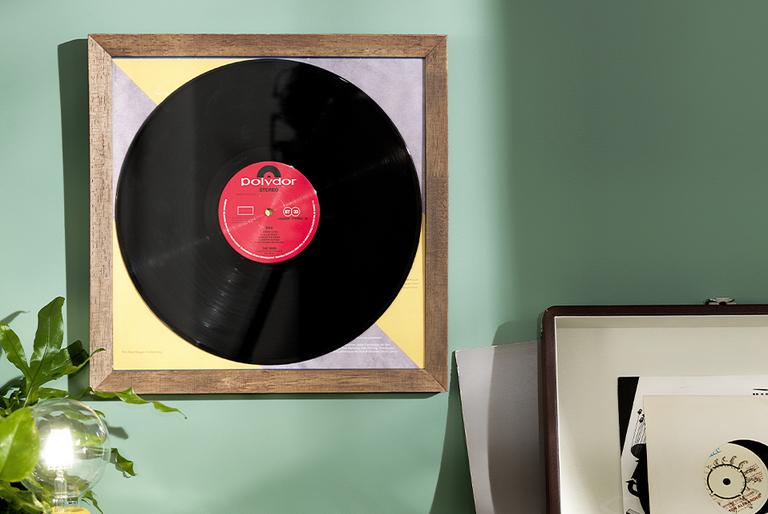 A framed vinyl record on a mint green wall.