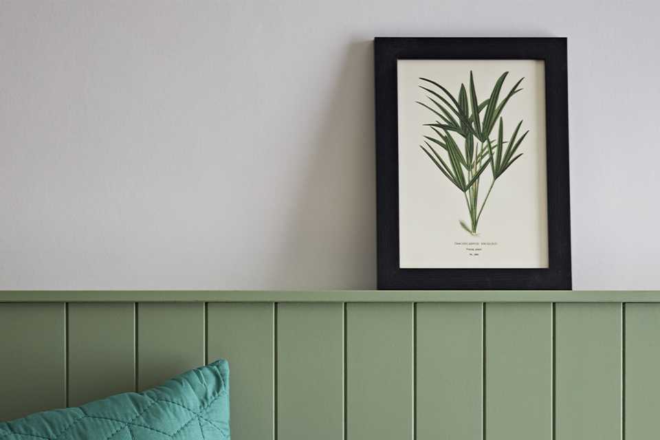 Black frame with wall art on green shelf.