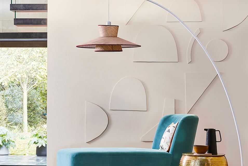 Image of a large arched floor lamp next to a turquoise chaise lounge.