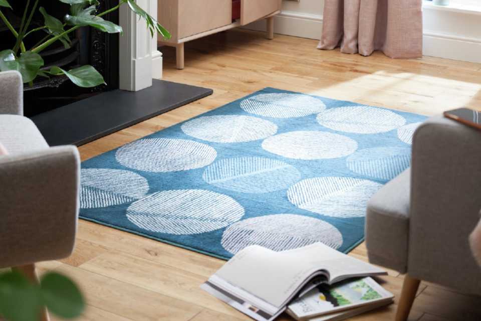 A blue rug with large cream circles on a wooden floor.
