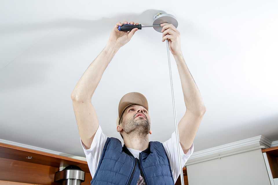 Man fitting a ceiling light to ceiling.