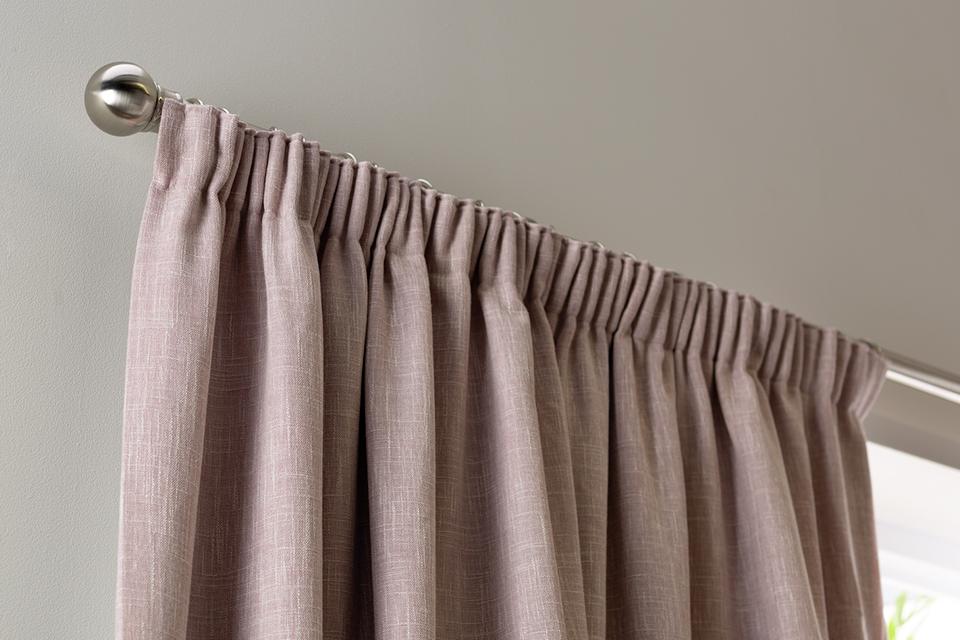 Pale pink pencil pleat curtains.