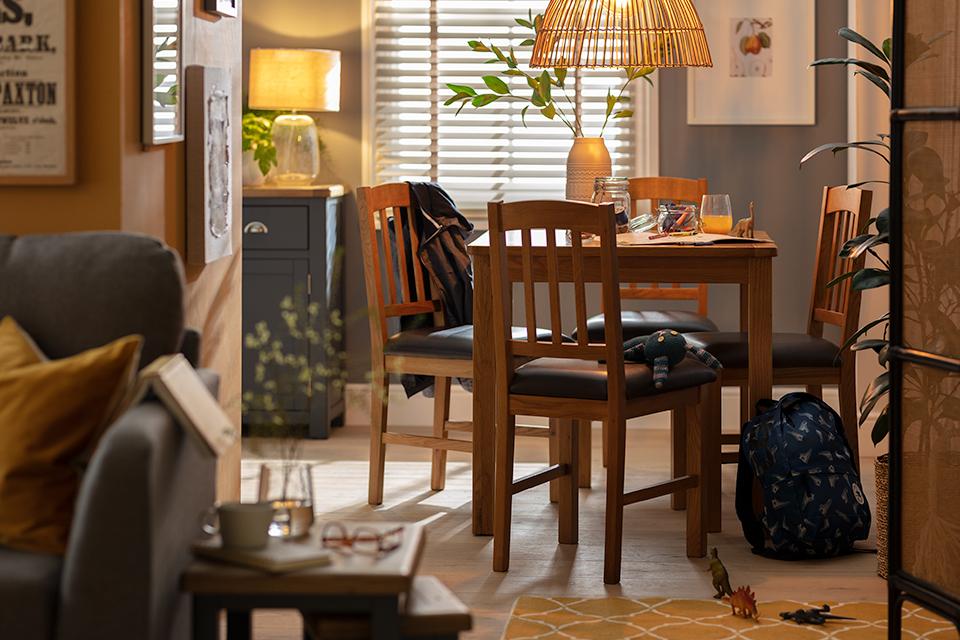 A square wooden dining set in a cosy living space.