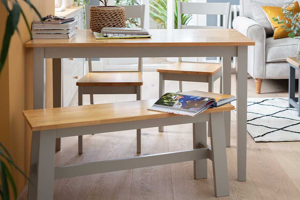A grey and wooden dining table with matching benches in an open plan living space.