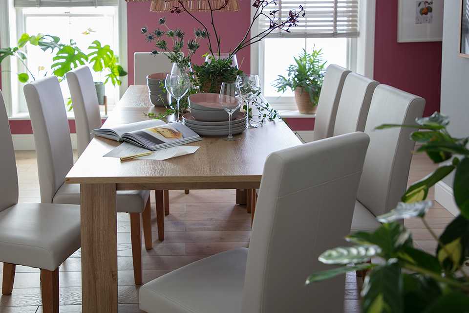 A long rectangular wooden dining table with matching upholstered chairs.