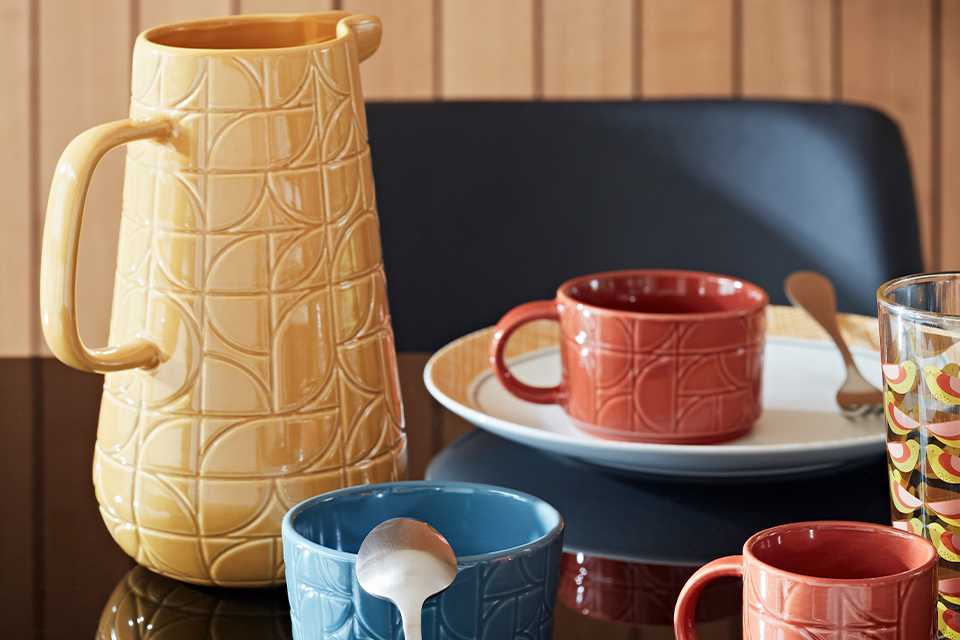 Mustard, terracotta and blue mugs and jug.