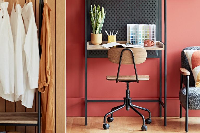 Image of small desk set up in a bedroom with terracotta walls.