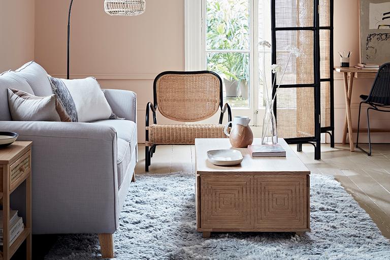 Living room with grey sofa and rattan armchair and screen.