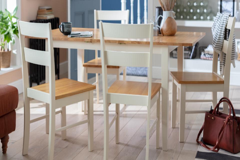 Oak and white dining tables with four matching chairs.