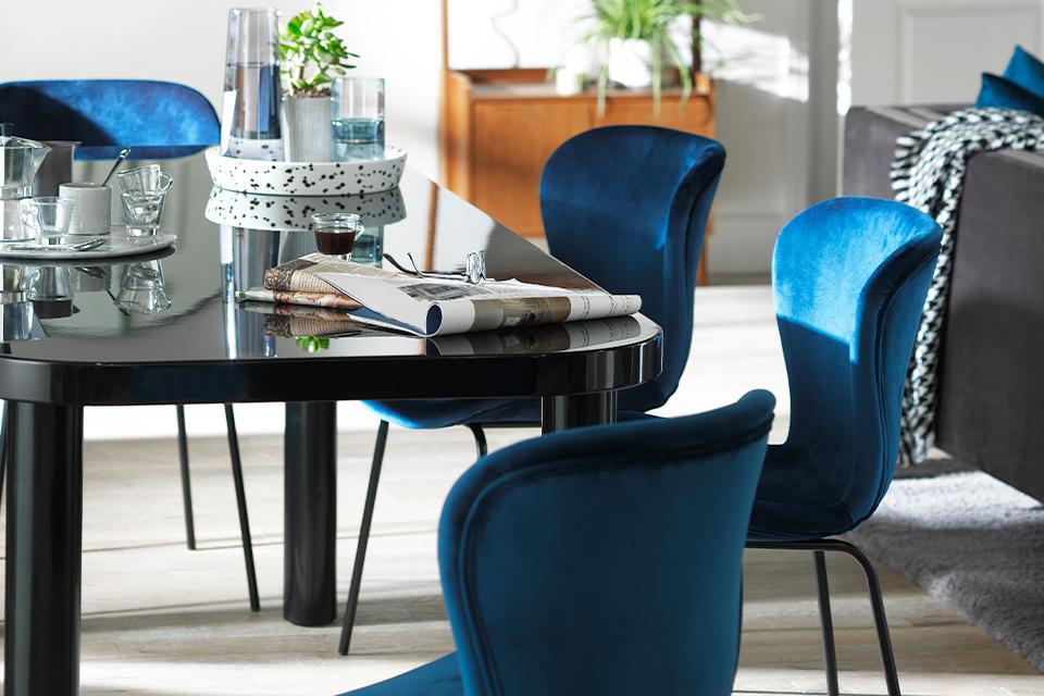 Black glossy dining table and blue velvet dining chairs.