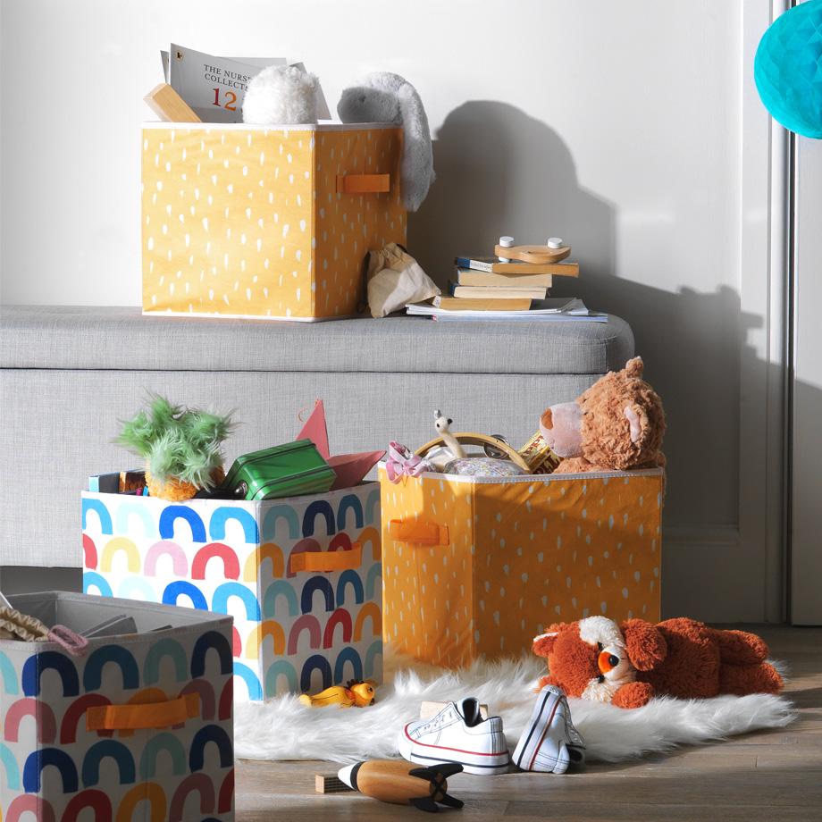 Rainbow and yellow fabric storage boxes, full of toys.