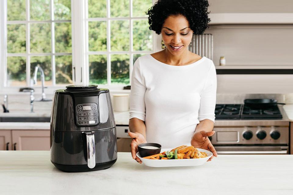 Woman using multi-cooker to prepare healthy meal.