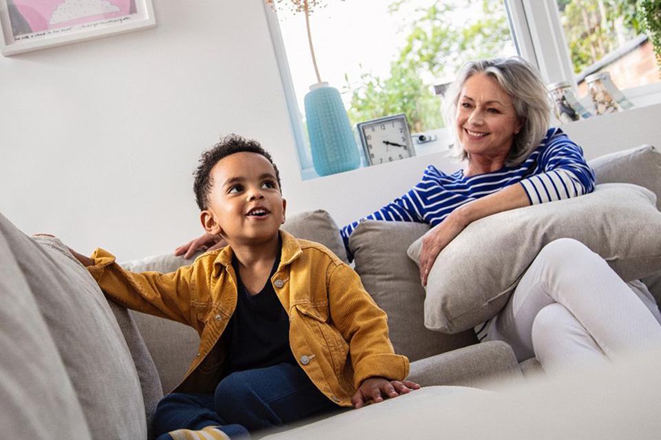 Toddler and parent sat on grey sofa.