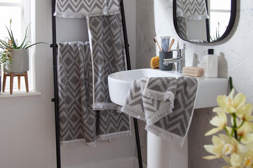 Grey and white diamond pattern towels hung on a black ladder shelf.