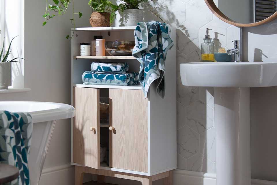 Blue patterned towels in bathroom stacked on cupboard.