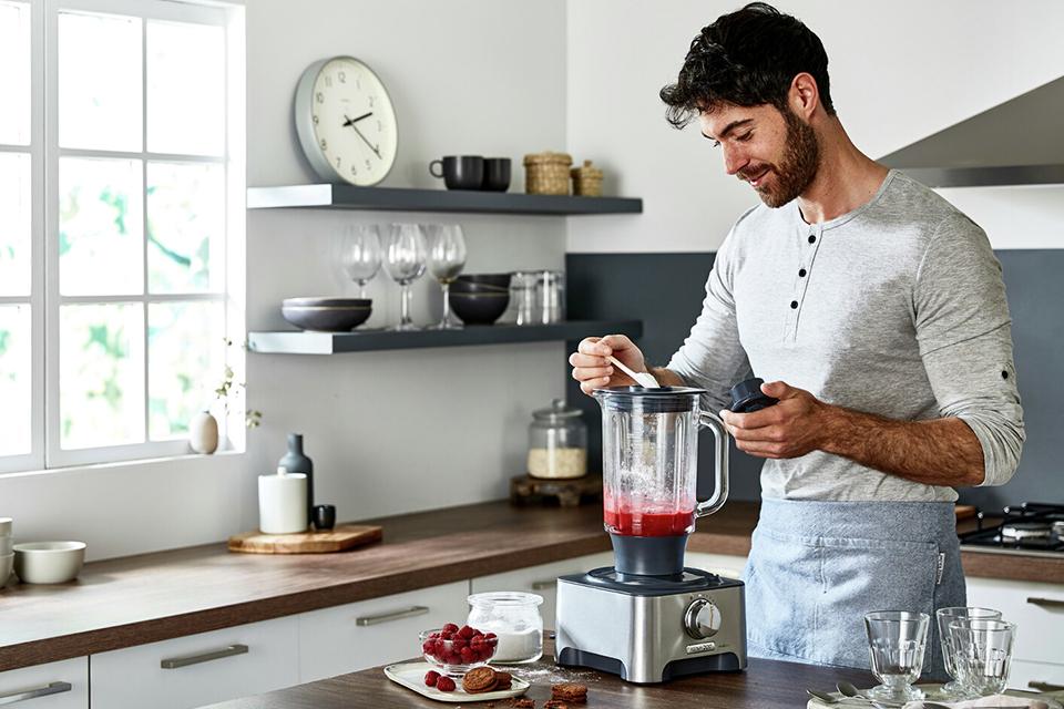 A man blending raspberries in the silver Kenwood Multipro classic food processor.