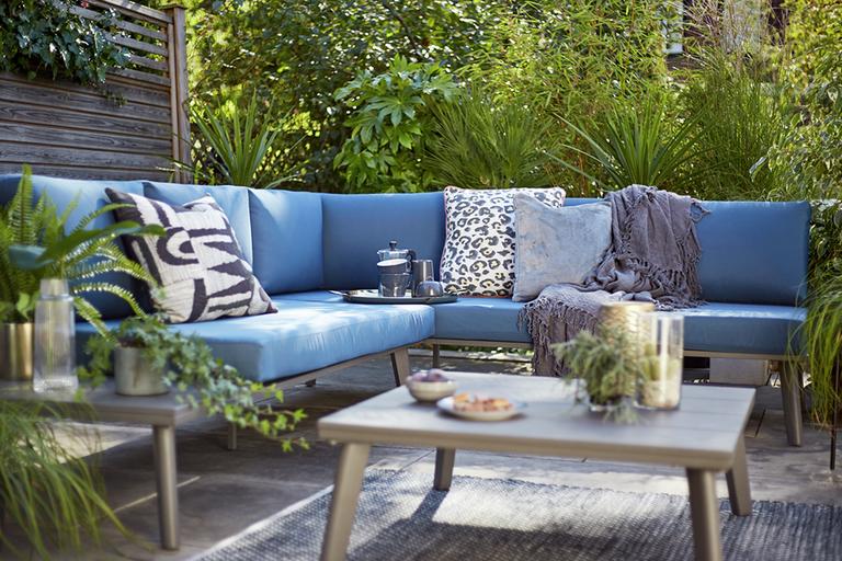 The Argos Home Jucar 5-seater corner sofa set in blue with cushions and throws on it.