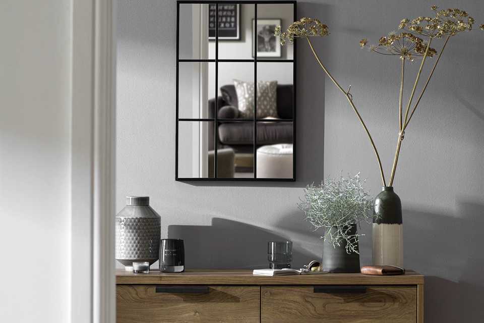 Hallway mirror hanging on wall with black frame.