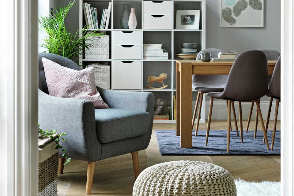 An open plan living space with a cube bookcase, a dining set, and an armchair.