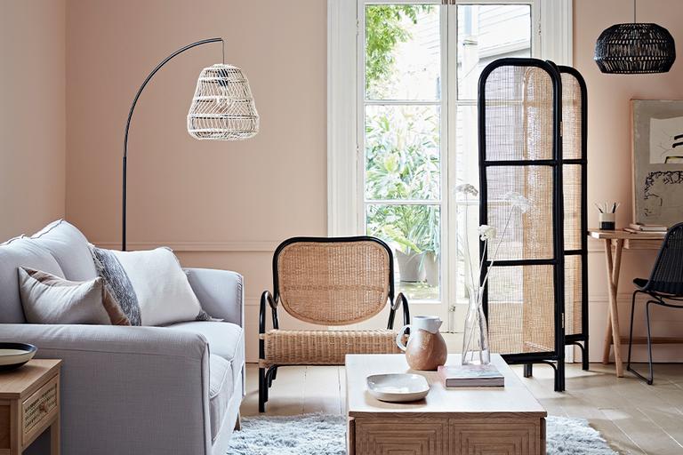 Living room with grey sofa and rattan armchair and screen.