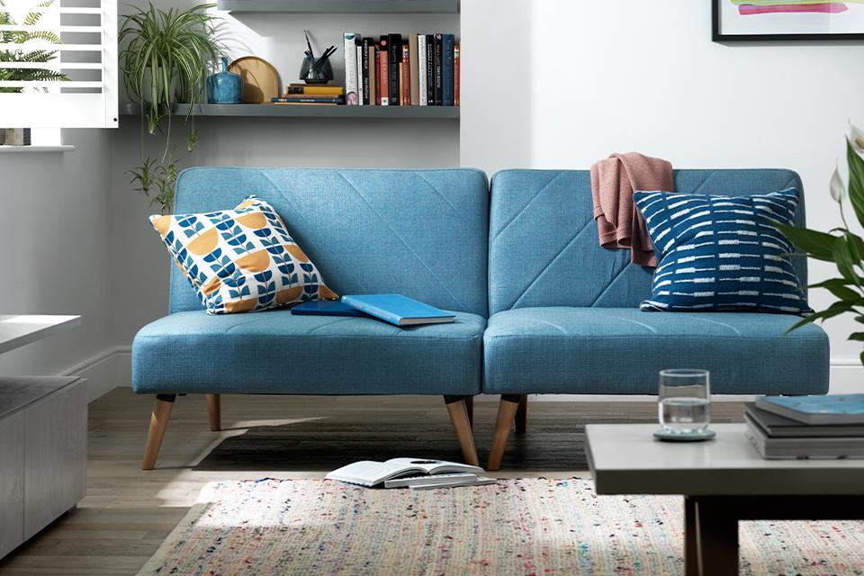 Image of a blue sofa bed in a white living room.