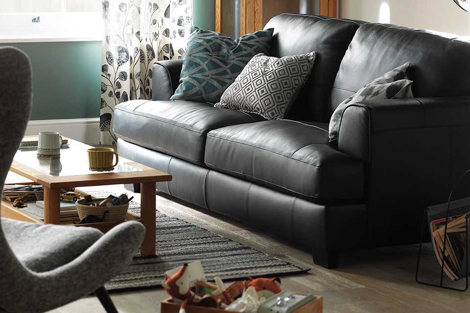 Image of black leather sofa with cushions in lounge.