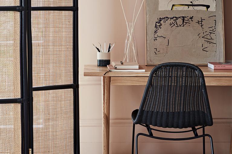 Oak desk with black rattan chair.
