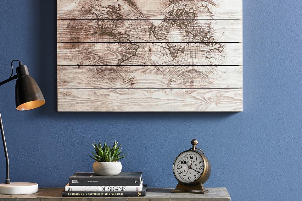 World map burned onto wood, hung on a wall above a desk.