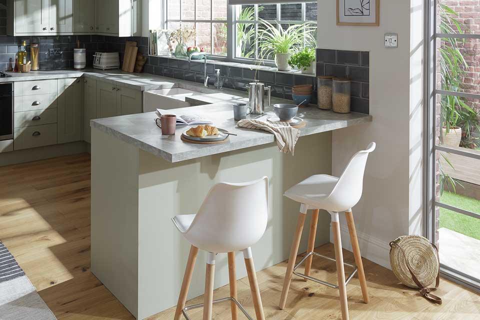 A modern and bright kitchen with a breakfast bar and two white bar stools.