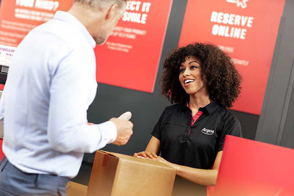 Argos store colleague serving customer at the till.