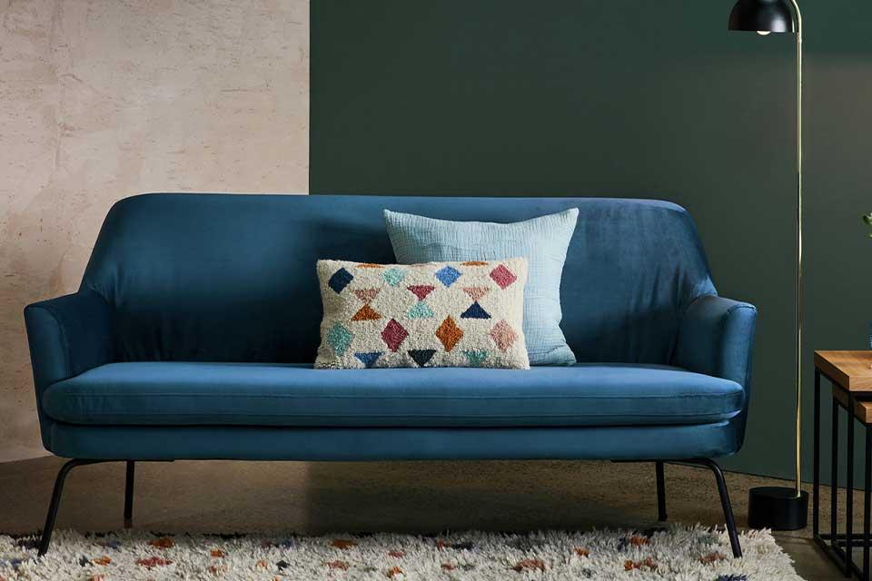 A blue Scandi-styled sofa in a lounge with a geometric rug in front.