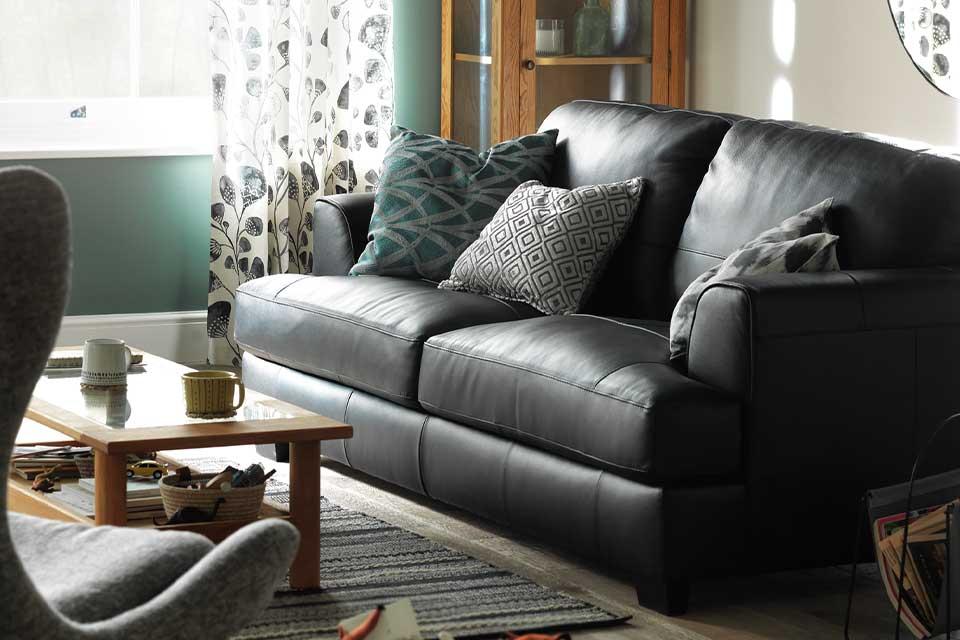 A black leather sofa in a cosy lounge setting.