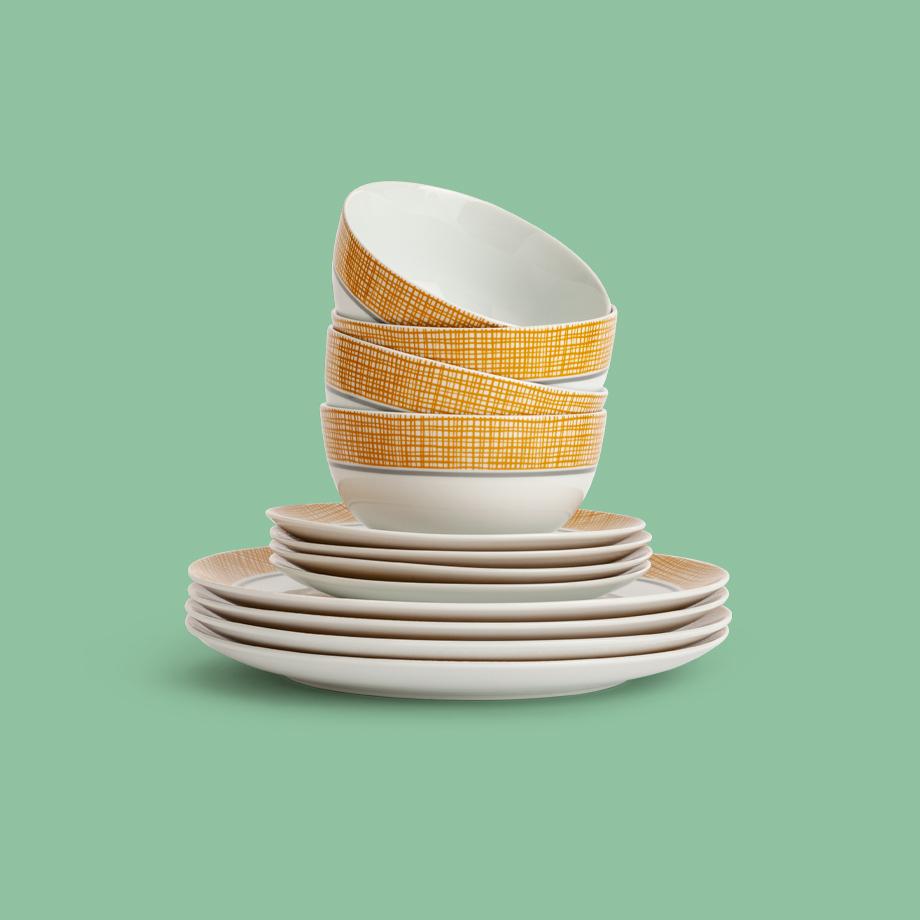 A white and yellow stack of bowls, side plates and dinner plates.