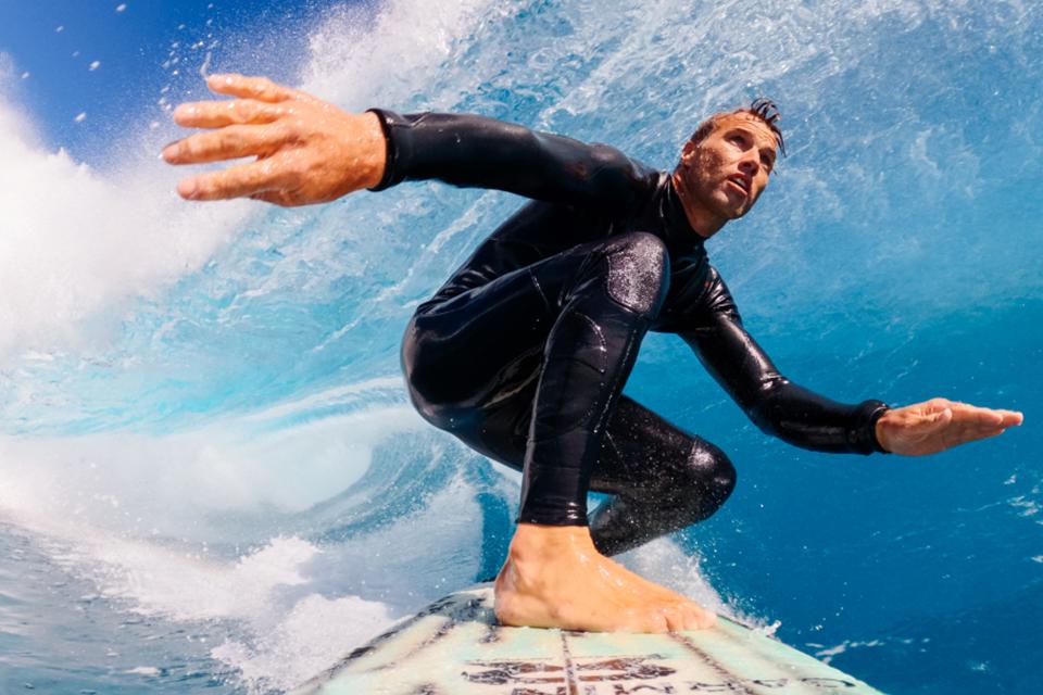 A surfer in a black wetsuit riding waves.