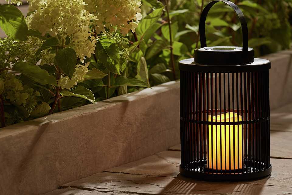 Garden by Sainsbury's solar flickering candle lantern placed outdoors next to a lawn edge.